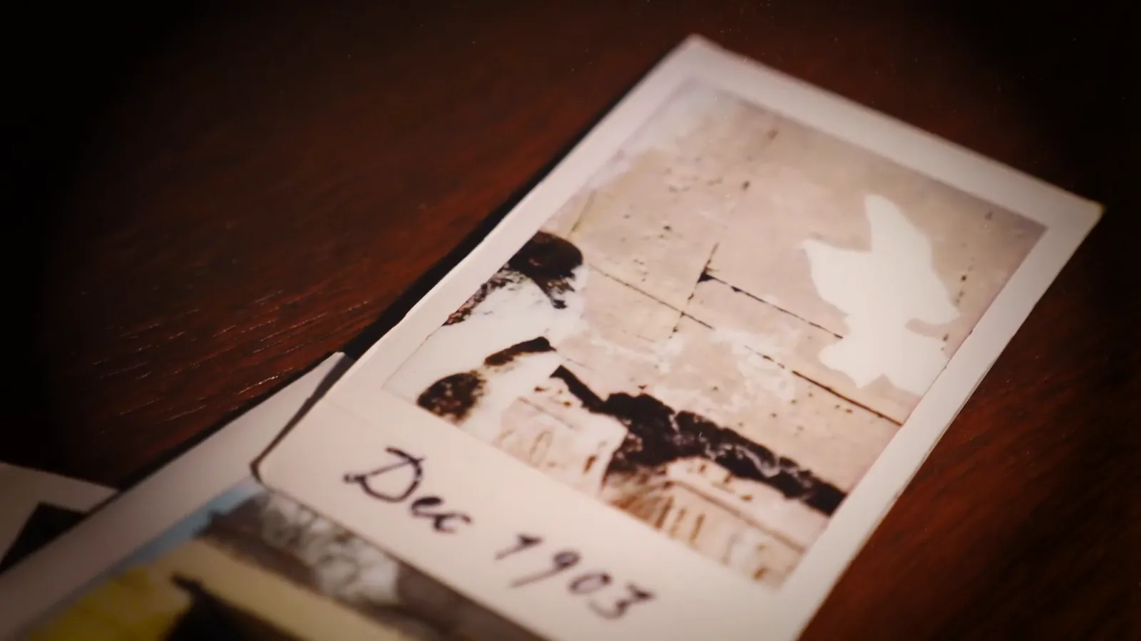 Faded expedition photographs dated December 1903 on a desk in Entombed