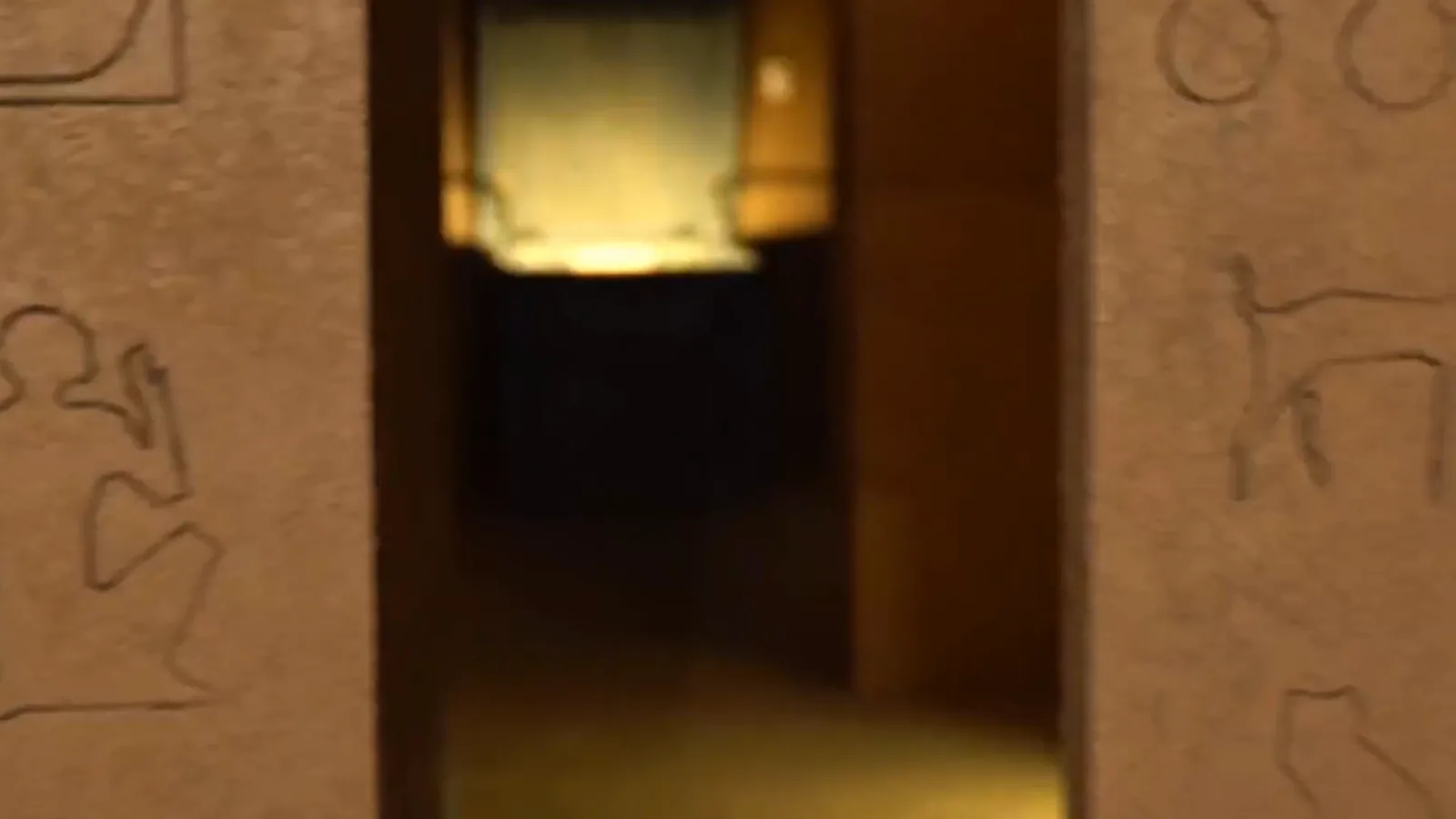 A lit doorway between carved sandstone walls inside Lost Tomb at Escape This Perth CBD