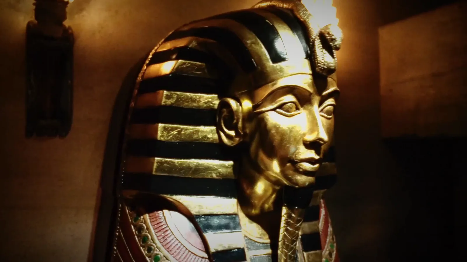 A gold and lapis pharaoh’s burial mask lit by torchlight in Entombed